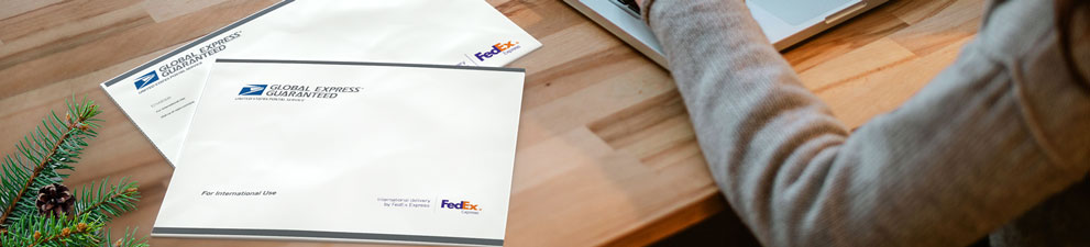 Person with laptop preparing to send two GXG envelopes for the holidays.